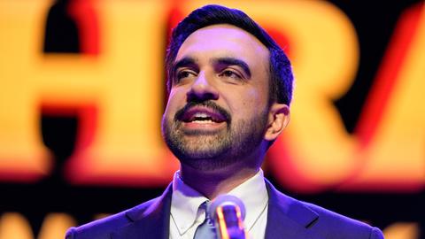 Zohran Mamdani spricht nach seinem Wahlsieg in einem blauen Anzug in New York auf der Bühne in ein Mikrofon. Sein Gesicht ist vor einem orange-roten Hintergrund zu sehen.
Zohran Mamdani spricht nach seinem Wahlsieg in einem blauen Anzug in New York auf der Bühne in ein Mikrofon. Sein Gesicht ist vor einem orange-roten Hintergrund zu sehen.