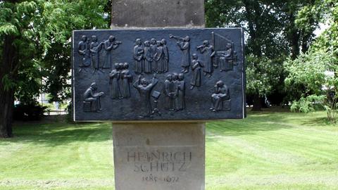 Auf dem Bild ist ein Denkmal aus einem großen senkrecht aufgestellten Stein zu sehen, auf dem eine schwarze Steintfafel montiert wurde. 