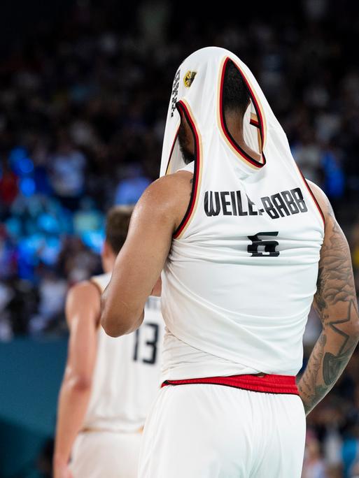 Der deutsche Basketball Nick Weiler-Babb zieht sich nach der Niederlage sein Trikot über den Kopf und versteckt so seinen Kopf. 