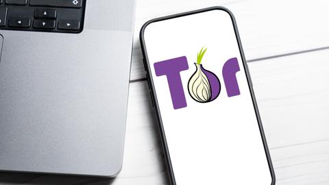 Das Tor-Netzwerk Logo wird auf einem Smartphone-Bildschirm neben einem Laptop angezeigt.