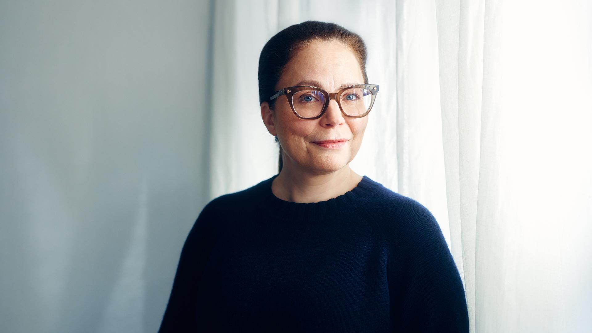 Thea Dorn, mit Brille und dunklem Pullover, steht vor einem Fenster und blickt in die Kamera. Thea Dorn, mit Brille und dunklem Pullover, steht vor einem Fenster und blickt in die Kamera.
