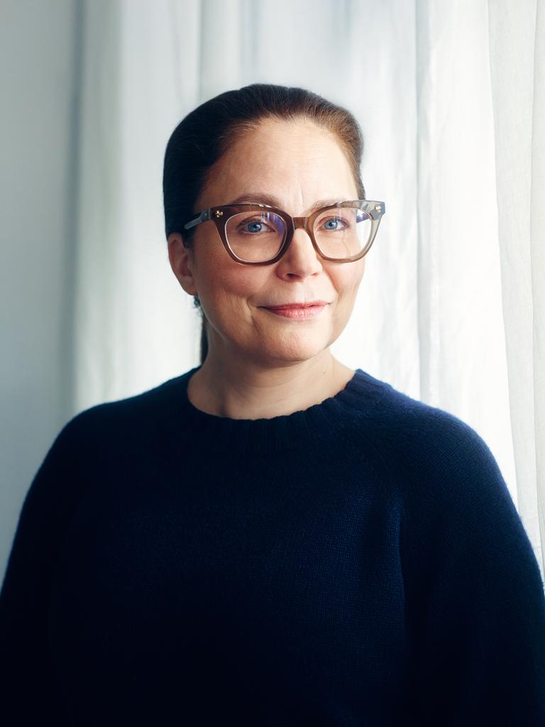 Thea Dorn, mit Brille und dunklem Pullover, steht vor einem Fenster und blickt in die Kamera.