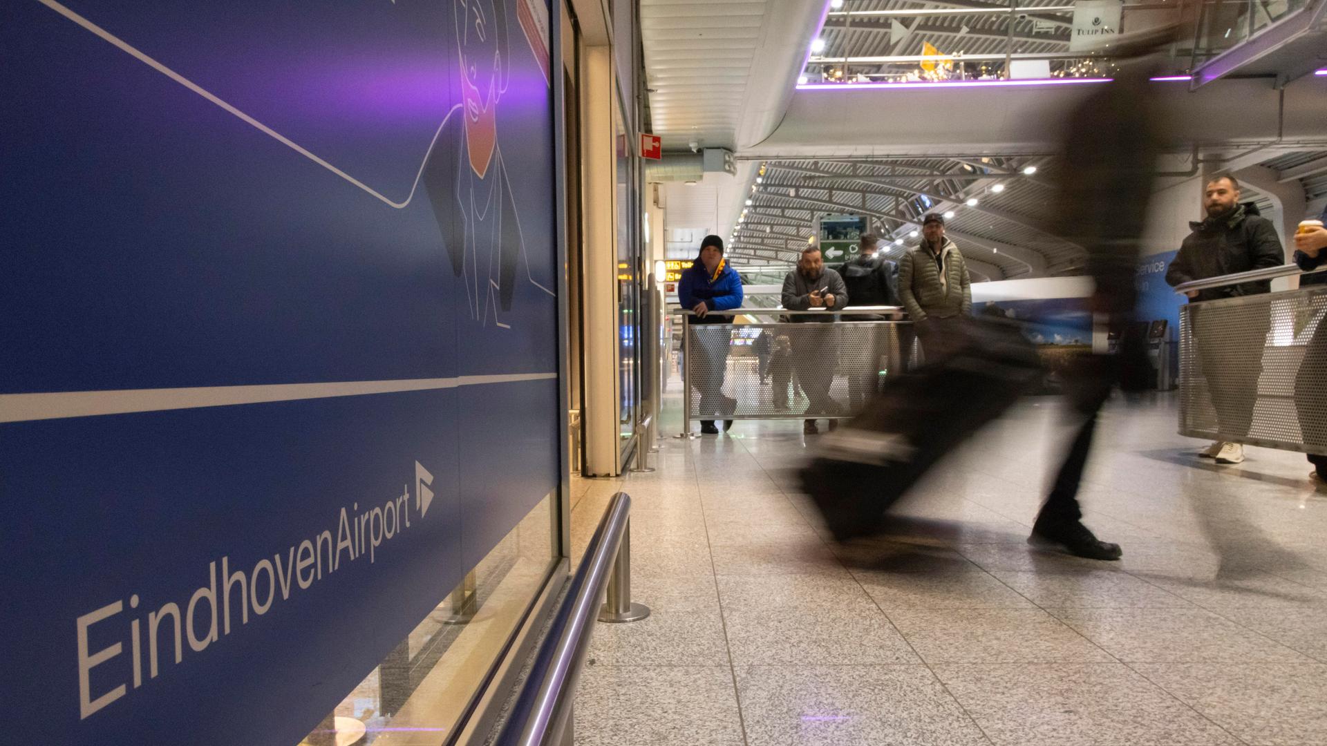 Abgebildet sind mehrere Menschen am Flughafen im niederländischen Eindhoven.