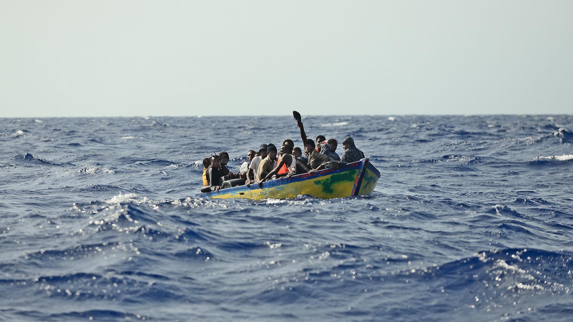 Ein Holzboot mit rund 30 Menschen treibt auf dem Meer