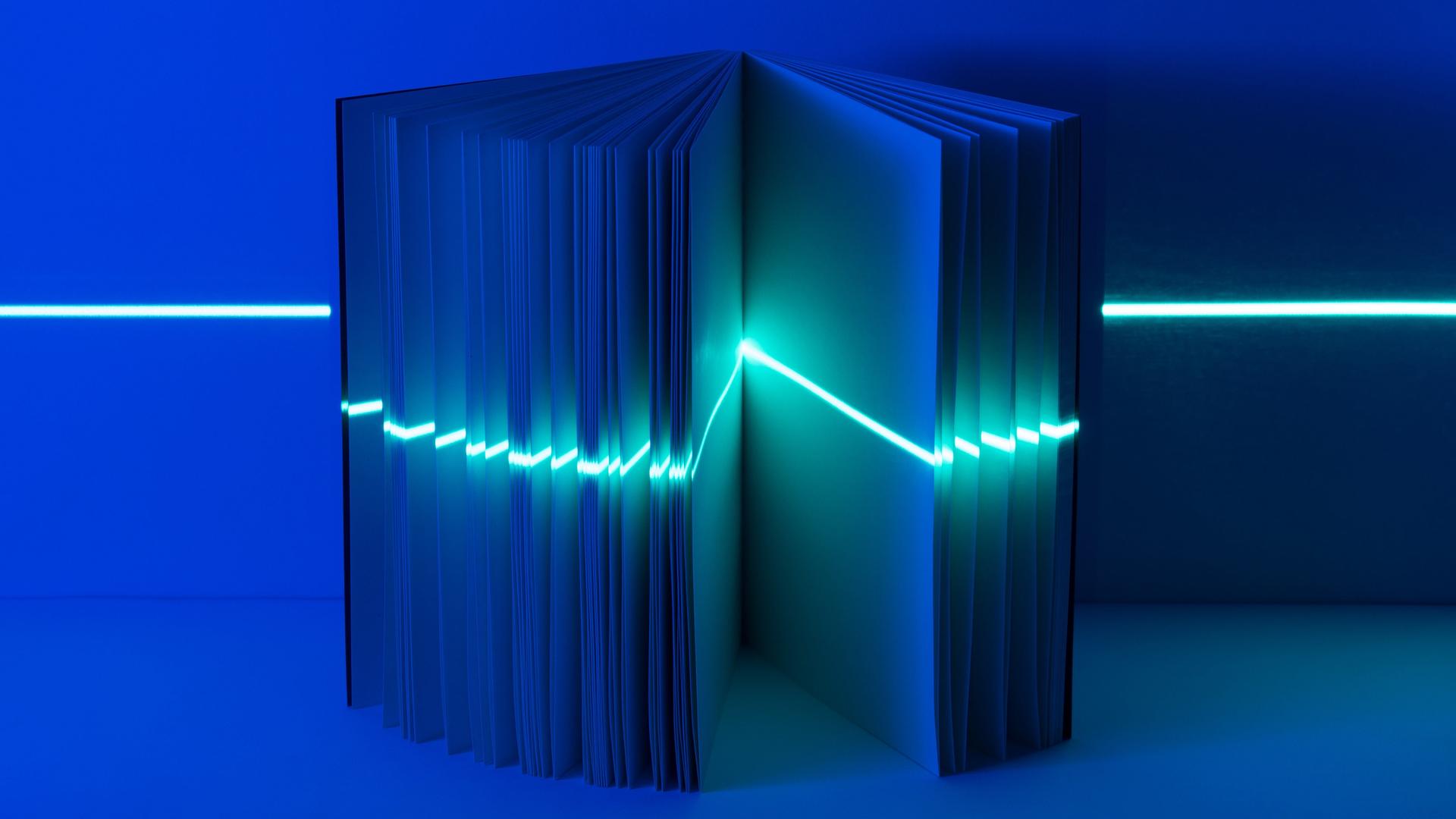 Ein geöffnetes Buch mit einem Lichtstrahl wie ein Laser, quer durch alle Seiten.