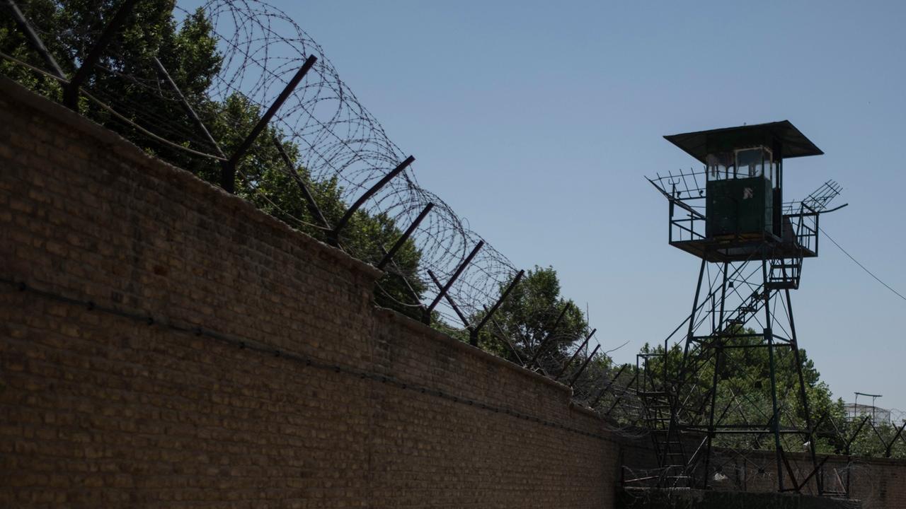 Mit Stacheldraht geschützte Außenmauer des Teheraner Evin-Gefängnisses sowie ein Wachturm.