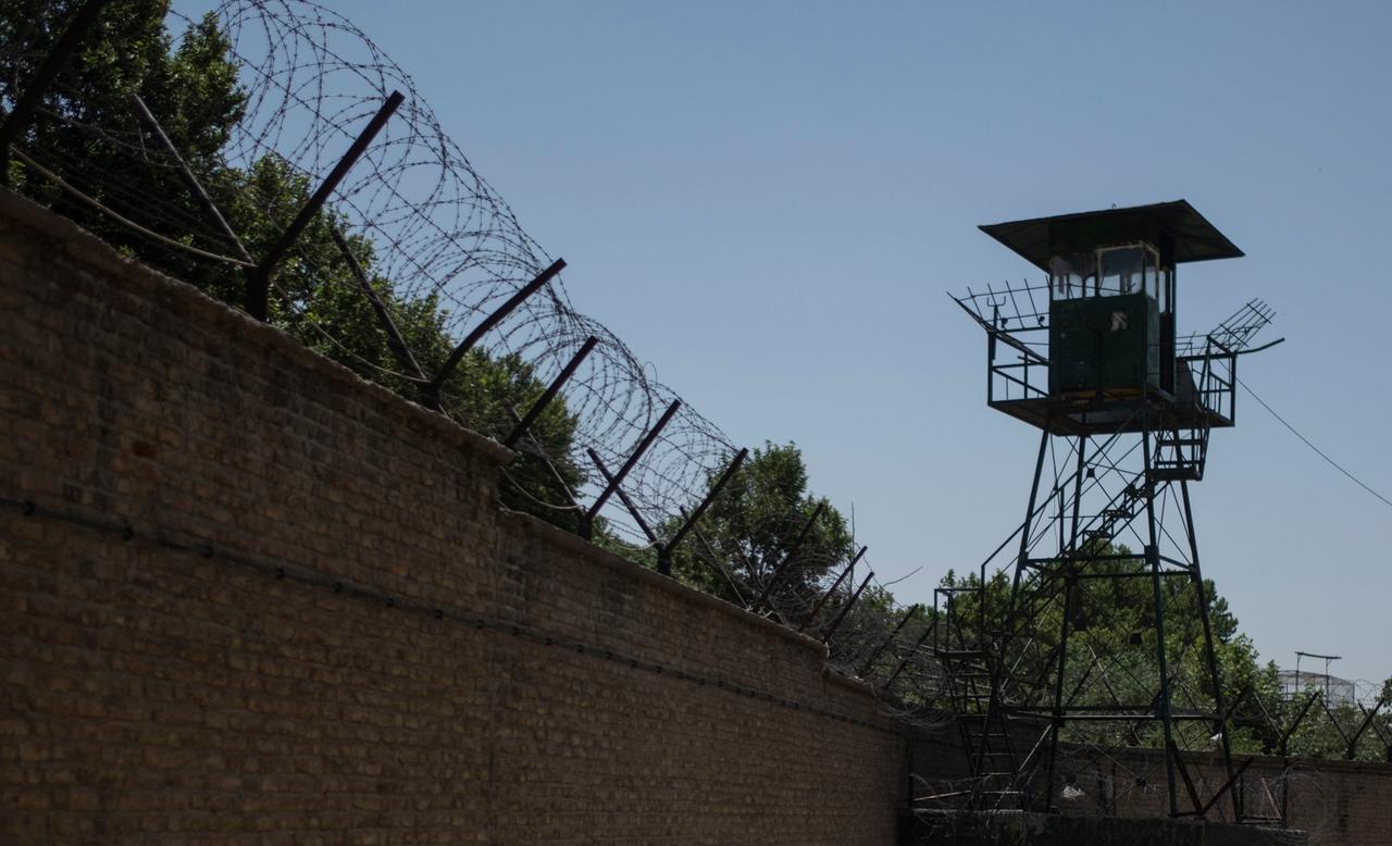 Mit Stacheldraht geschützte Außenmauer des Teheraner Evin-Gefängnisses sowie ein Wachturm.
