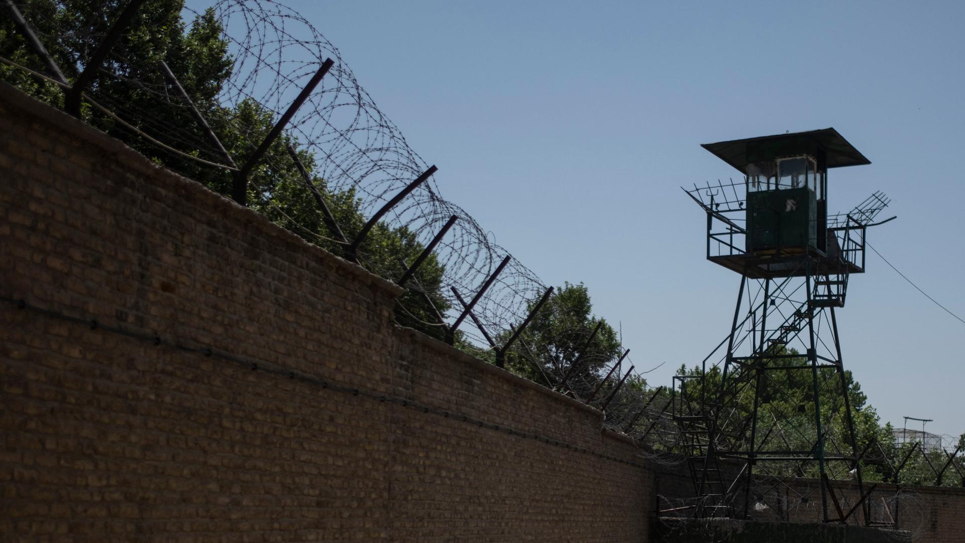 Mit Stacheldraht geschützte Außenmauer des Teheraner Evin-Gefängnisses sowie ein Wachturm.