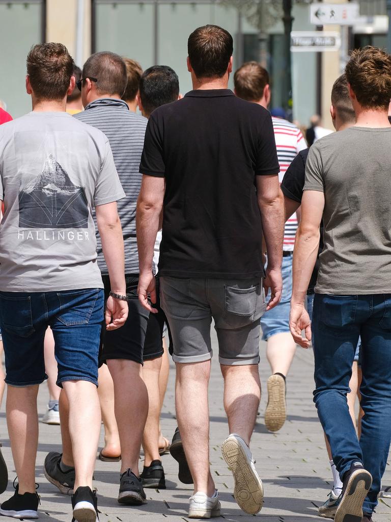 Junge Männer laufen durch die Innenstadt in Düsseldorf (zu sehen von hinten)