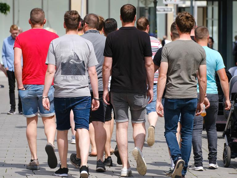 Junge Männer laufen durch die Innenstadt in Düsseldorf (zu sehen von hinten)