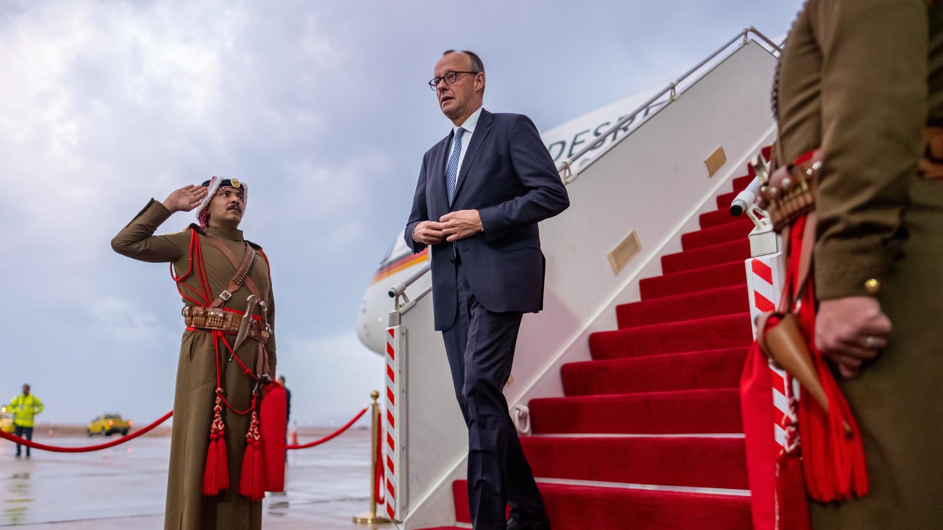 Bundeskanzler Friedrich Merz kommt die Gangway herunter und wird von einem jordanischen Vertreter begrüßt
