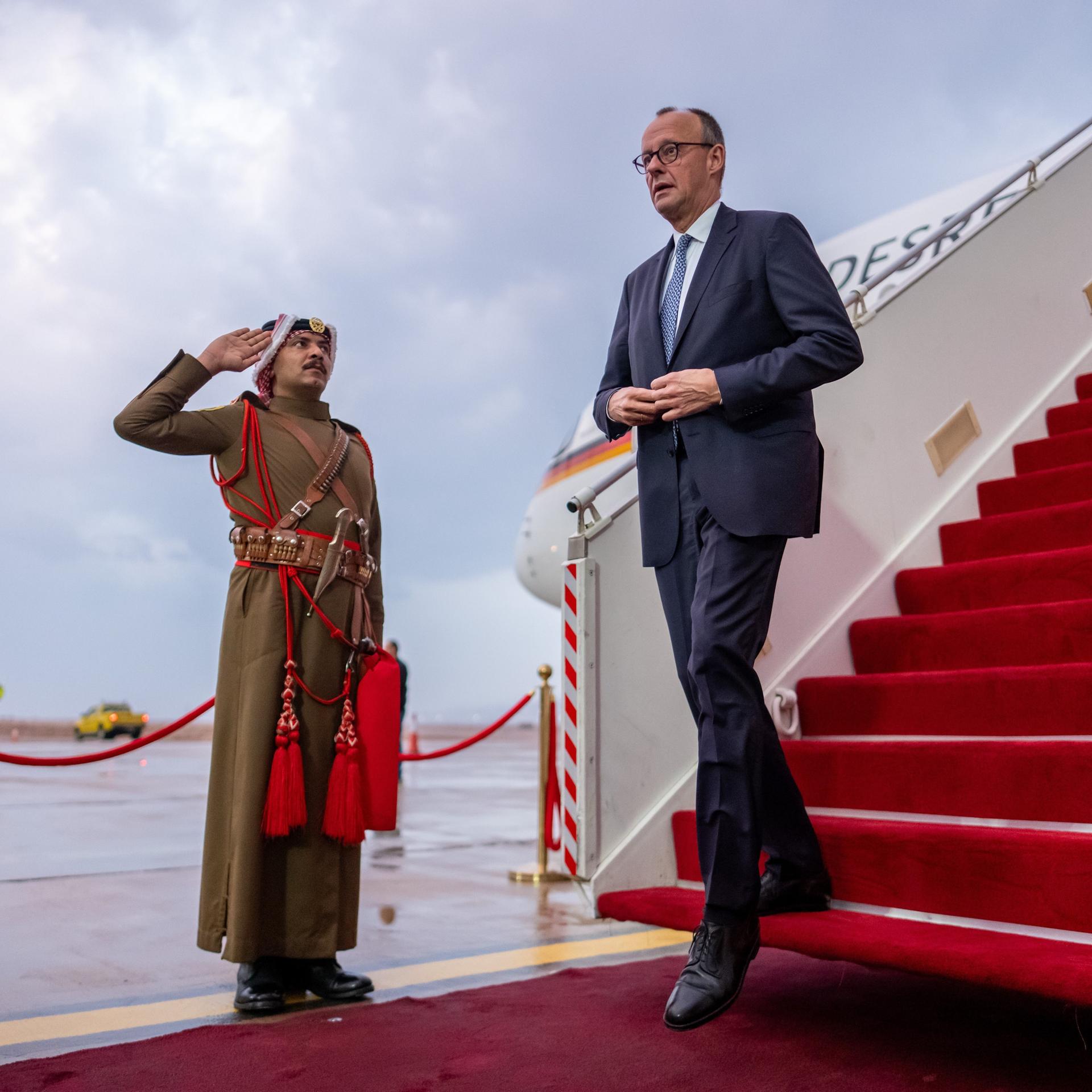 Bundeskanzler Friedrich Merz kommt die Gangway herunter und wird von einem jordanischen Vertreter begrüßt
