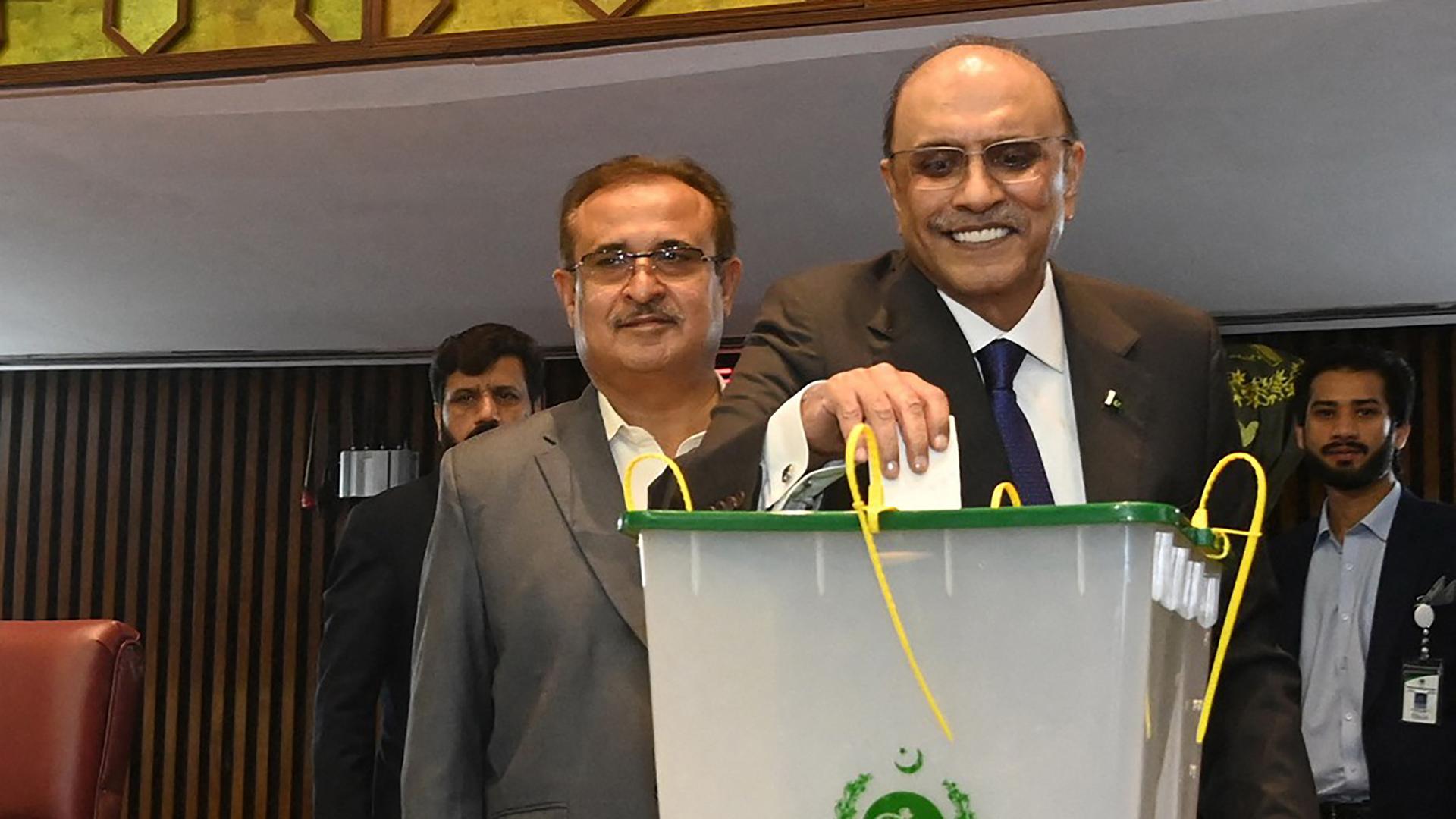 Asif Ali Zardari steckt einen Abstimmungszettel in eine Wahlurne. Er lächelt.