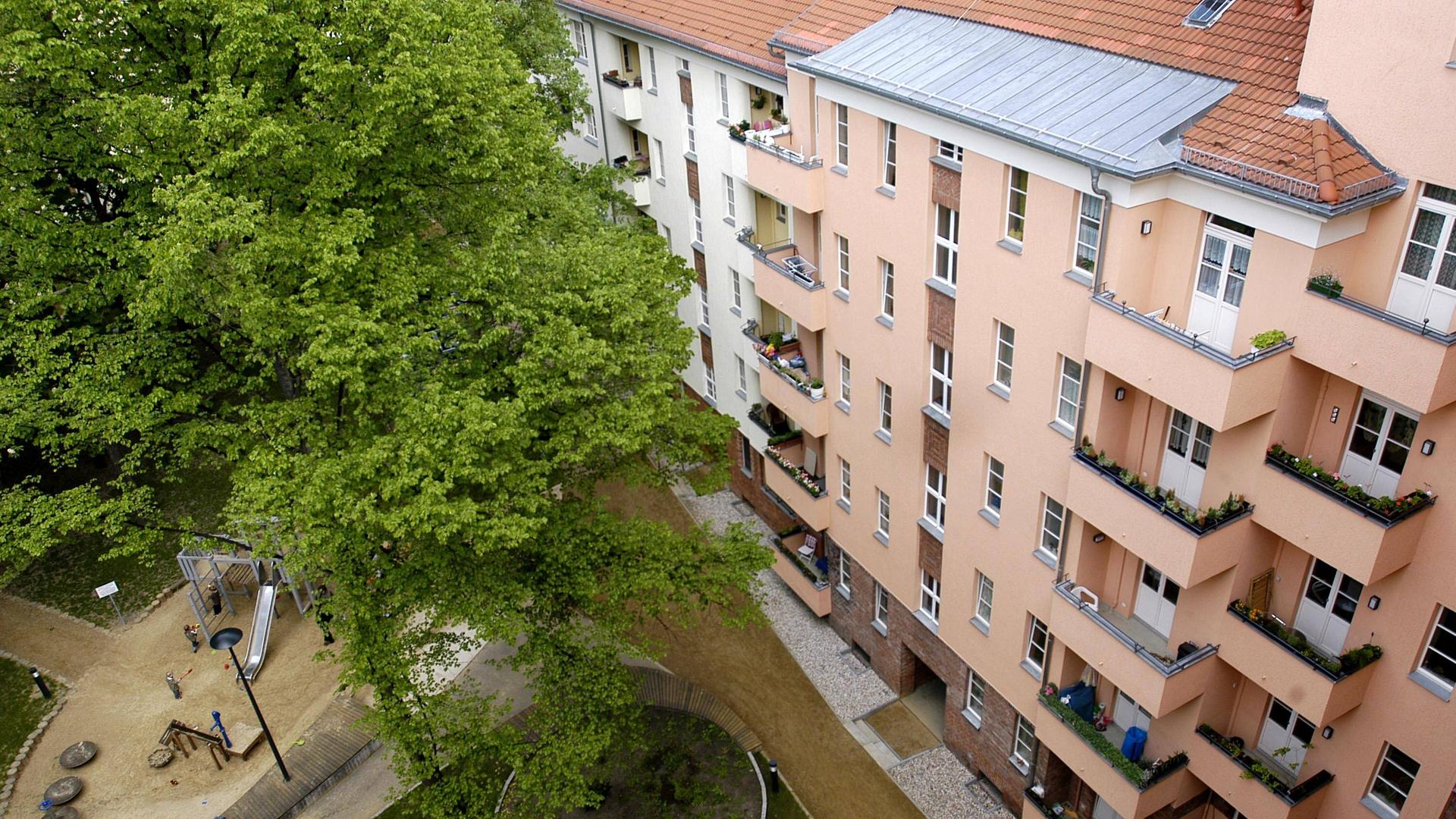 Innenhof eines Mehrfamilienhauses mit großem Garten und grünen Bäumen