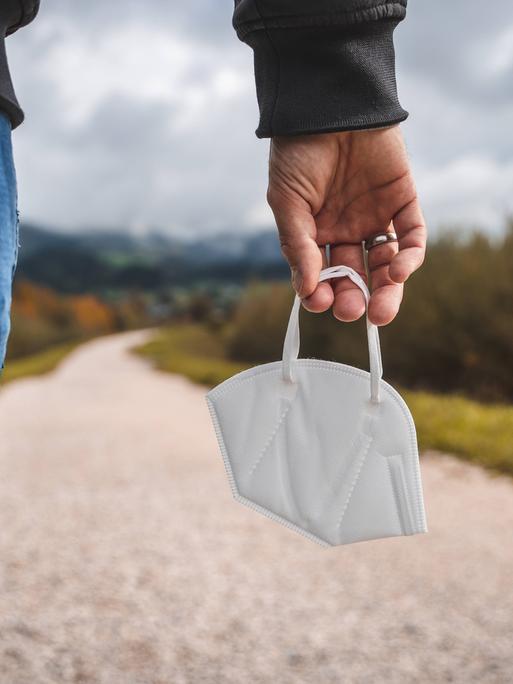 Ein Mensch hält eine FFPS-Maske in der Hand. 