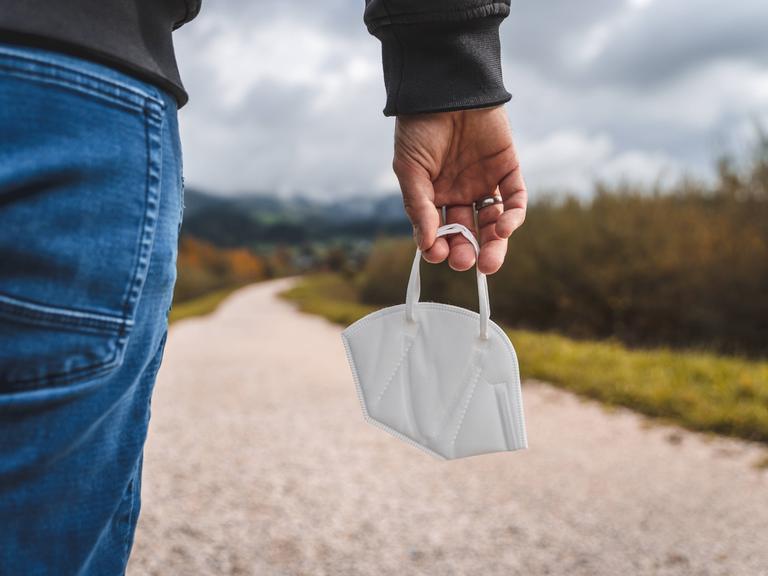 Ein Mensch hält eine FFPS-Maske in der Hand. 