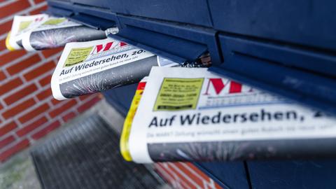 Mehrere Anzeigenblätter schauen aus blauen Briefkastenschlitzen hervor.