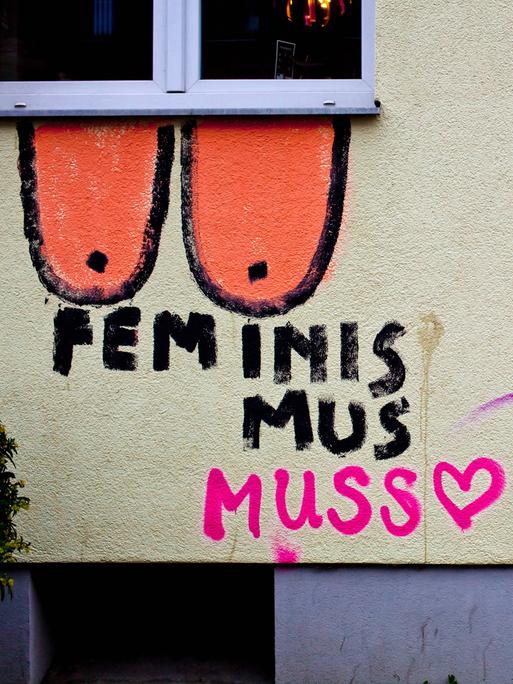 An einer Wand ist ein Grafitto gesprüht mit "Feminismus muss" und der Ergänzung "nicht sein". Dazu wurden Brüste gemalt.