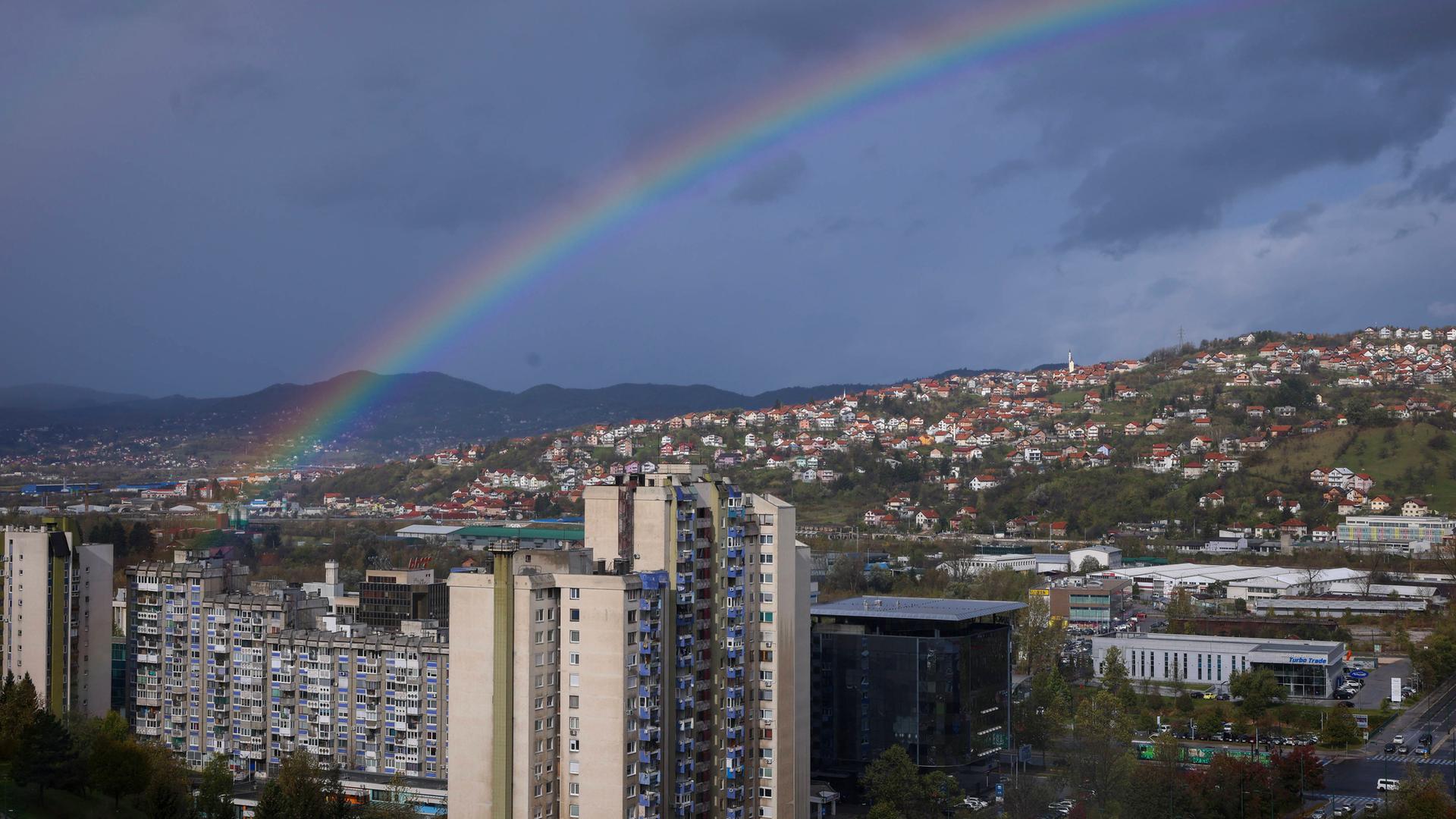 Blick auf die bosnische Hauptstadt Sarajewo über der gerade ein Regenbogen zu sehen ist. 