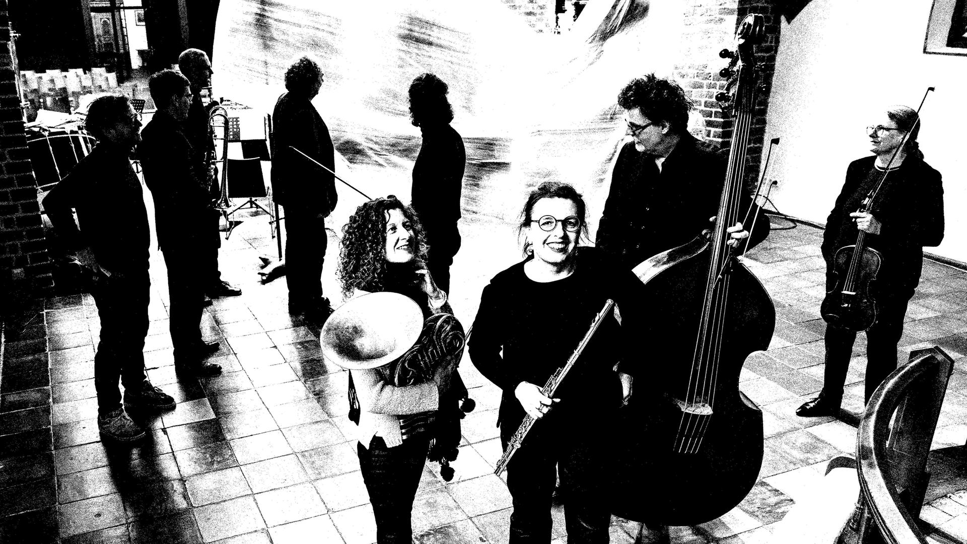 Ensemblemusiker stehen mit ihren Instrumenten im Kirchenraum verteilt. Ensemblemusiker stehen mit ihren Instrumenten im Kirchenraum verteilt.