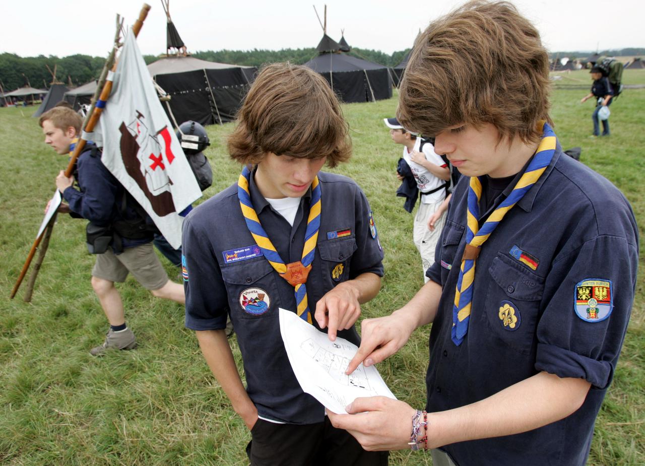 Pfadfinder suchen sich auf dem Bundeslager am Mittwoch (27.07.2005) in Almke bei Wolfsburg ihren Lagerplatz. Zwei Jungen studieren eine Karte, im Hintergrund stehen aufgebaute Zelte. 