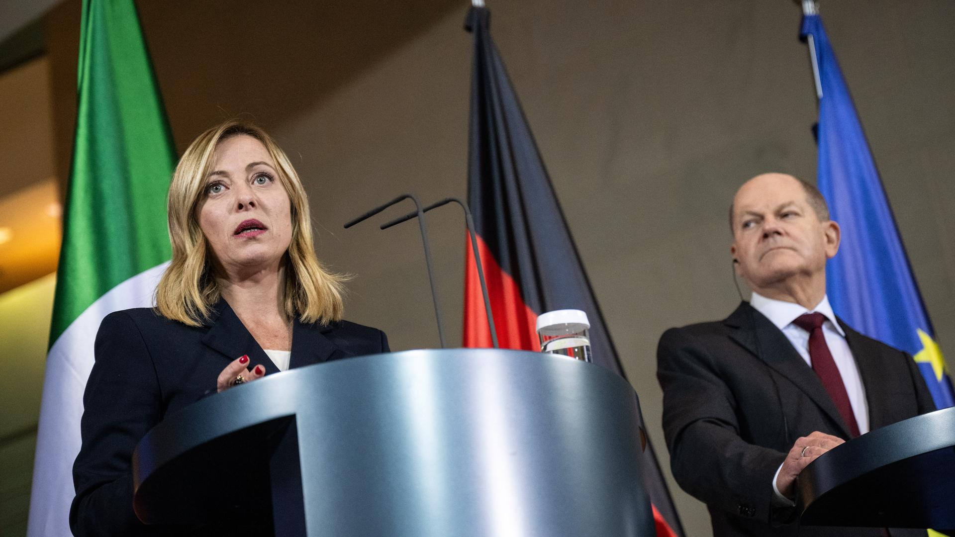 Die italienische Ministerpräsidentin Giorgia Meloni und Bundeskanzler Olaf Scholz stehen an Pulten. Im Hintergrund die Fahnen von Italien, Deutschland und EU.