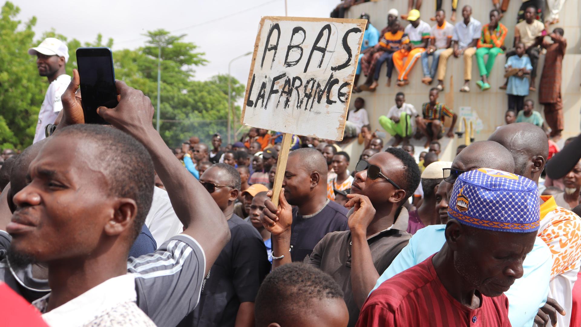 Menschen demonstrieren in Nigers Hauptstadt Niamey, um damit ihre Unterstützung für die Putschisten zu zeigen. Ein junger Mann hält dabei ein Schild mit der Aufschrift «A bas la France» (Nieder mit Frankreich) hoch. Bei der Demonstration wurden auch Parolen gegen die ehemalige Kolonialmacht Frankreich gerufen