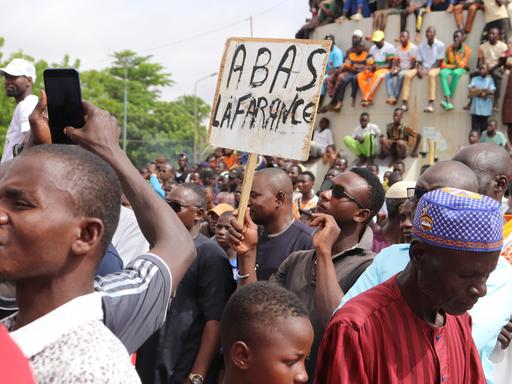 Menschen demonstrieren in Nigers Hauptstadt Niamey, um damit ihre Unterstützung für die Putschisten zu zeigen. Ein junger Mann hält dabei ein Schild mit der Aufschrift «A bas la France» (Nieder mit Frankreich) hoch. Bei der Demonstration wurden auch Parolen gegen die ehemalige Kolonialmacht Frankreich gerufen