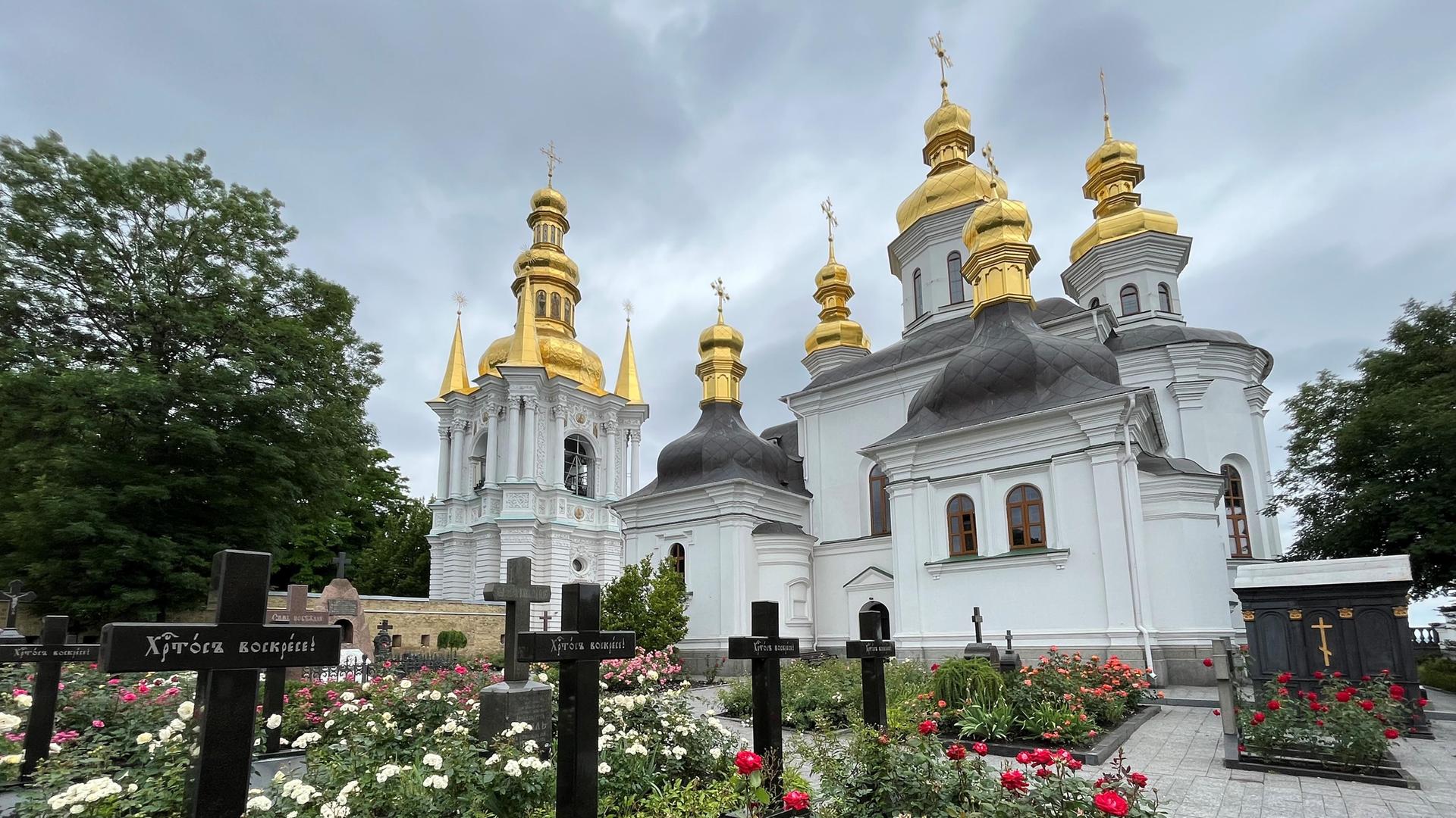12.06.2023, Ukraine, Kiew: Auf dem Gelände des Höhlenklosters stehen Kirchengebäude und auf einem Friedhof mit Gräbern Kreuze. 12.06.2023, Ukraine, Kiew: Auf dem Gelände des Höhlenklosters stehen Kirchengebäude und auf einem Friedhof mit Gräbern Kreuze.