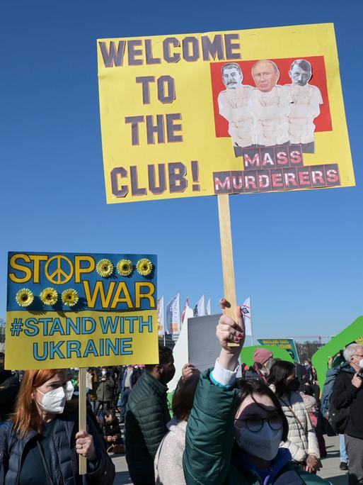 Demonstration gegen den Krieg von Wladimir Putin in der Ukraine halten ein Plakat in die Luft, auf dem sie Putin mit Stalin und Hitler vergleichen.
