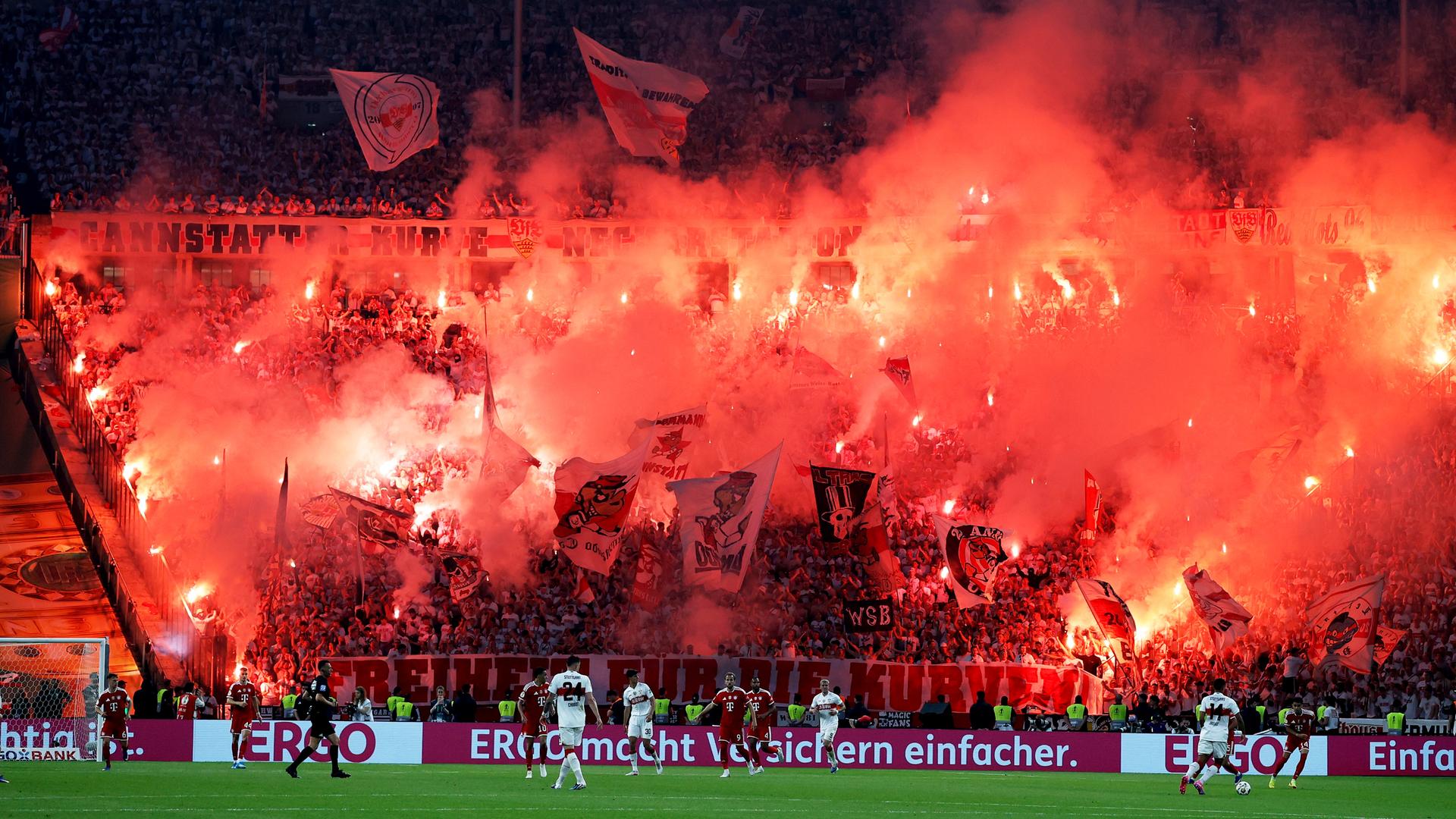 Das Bild zeigt die Fankurve vom VfB Stuttgart. Viele Fans haben rote Pyrotechnik gezündet, der Rauch zieht durch die Ränge. Das Bild zeigt die Fankurve vom VfB Stuttgart. Viele Fans haben rote Pyrotechnik gezündet, der Rauch zieht durch die Ränge.