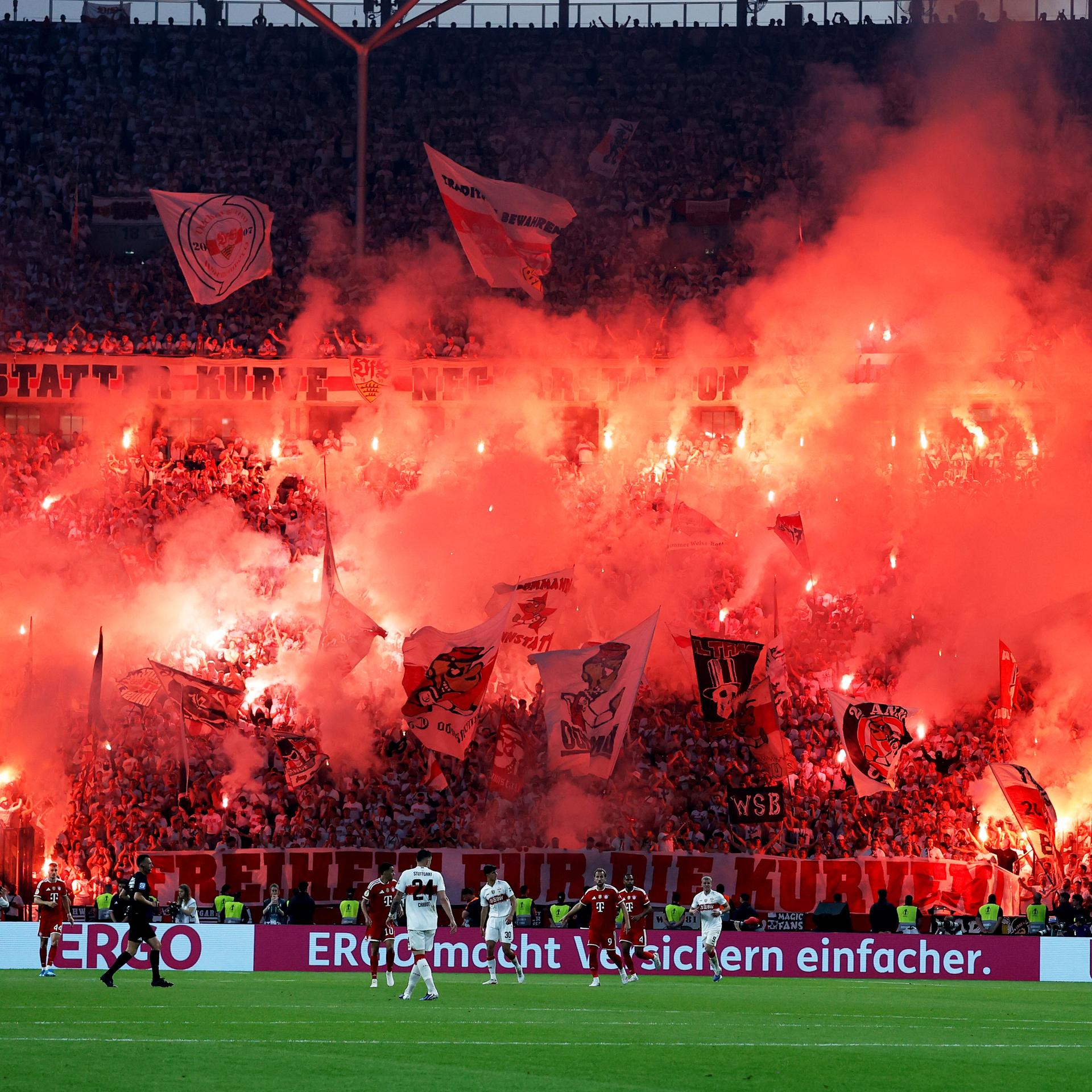 Das Bild zeigt die Fankurve vom VfB Stuttgart. Viele Fans haben rote Pyrotechnik gezündet, der Rauch zieht durch die Ränge.