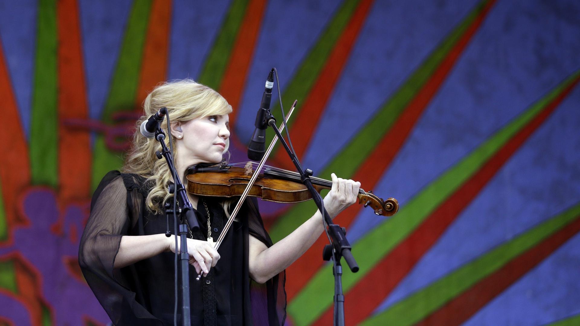 Alison Krauss steht mit ihrer Geige auf einer Bühne und spielt ihr Instrument.