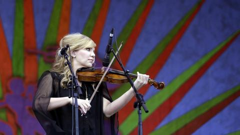 Alison Krauss steht mit ihrer Geige auf einer Bühne und spielt ihr Instrument.