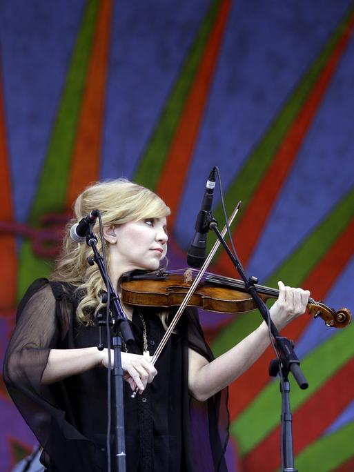Alison Krauss steht mit ihrer Geige auf einer Bühne und spielt ihr Instrument.