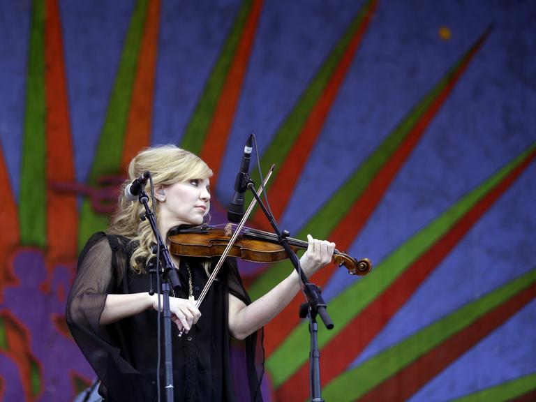 Alison Krauss steht mit ihrer Geige auf einer Bühne und spielt ihr Instrument.