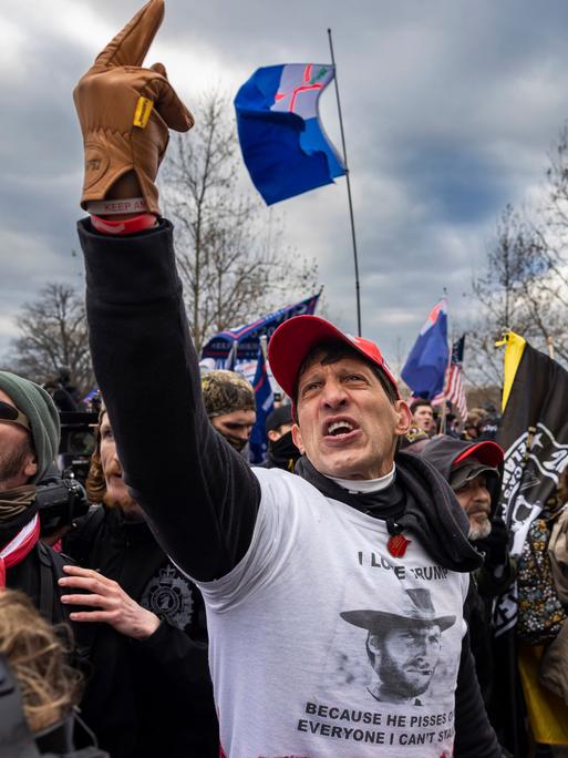 Eine Gruppe von US-Amerikanern sind zu einer Kundgebung versammelt. Sie scheinen wütend und aufgebracht zu sein. Eine Person in der Mitte hält schreiend den Mittelfinger in die Luft. Eine Gruppe von US-Amerikanern sind zu einer Kundgebung versammelt. Sie scheinen wütend und aufgebracht zu sein. Eine Person in der Mitte hält schreiend den Mittelfinger in die Luft.