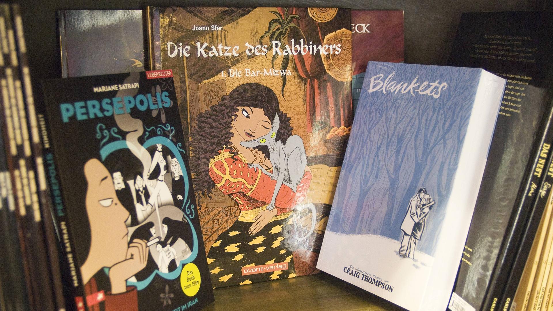 Die Comics "Die Katze des Rabbiners" von dem Franzosen Joann Sfar, "Persepolis" von der in Frankreich lebenden Iranerin Marjane Satrapi und "Blankets" von dem US-Amerikaner Craig Thompson stehen in einem Regals eines Comicladens.