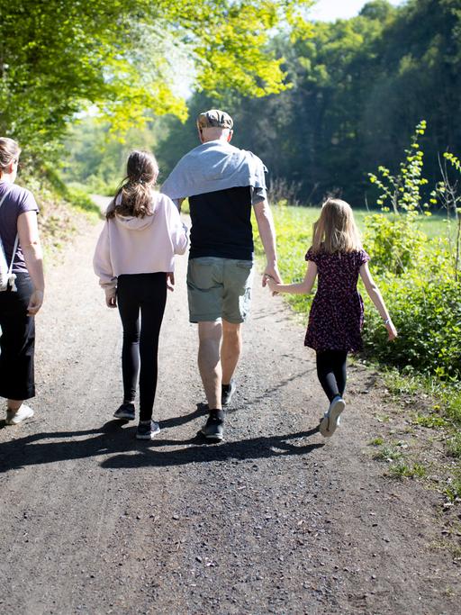 Eltern mit zwei Kindern gehen in der Natur spazieren.