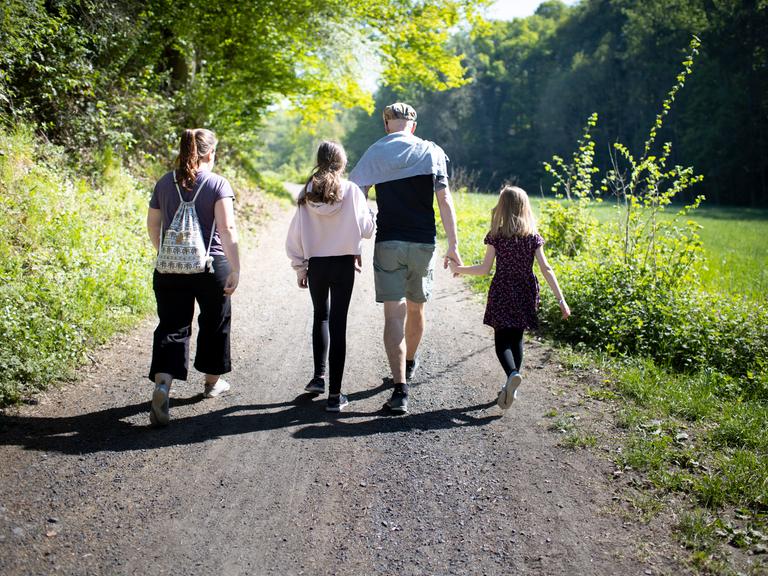 Eltern mit zwei Kindern gehen in der Natur spazieren.