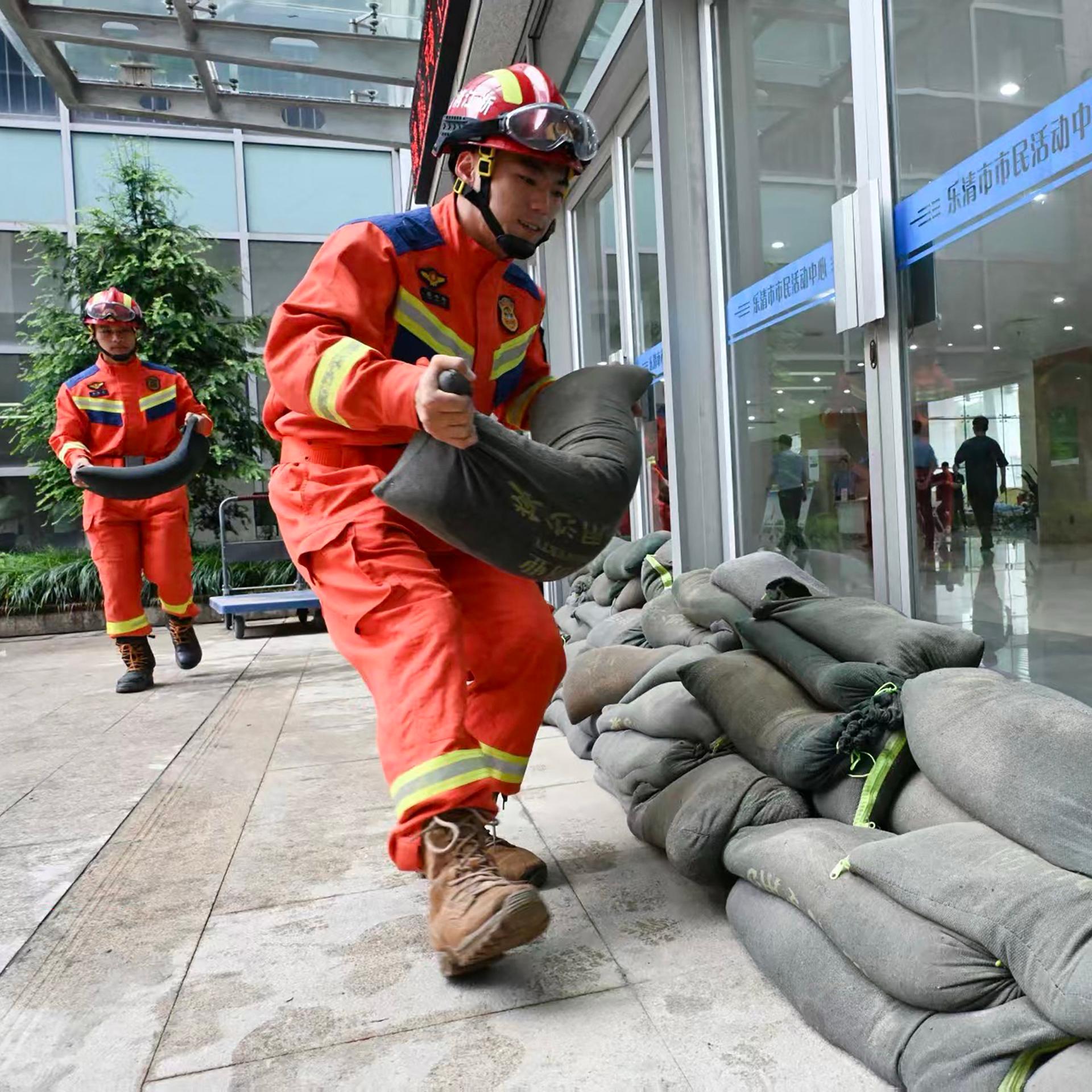 Feuerwehrleute in China legen in der Provinz Zhejiang Sandsäcke aus, um Fenster und Türen vor dem herannahenden Taifun Bavi zu sichern.