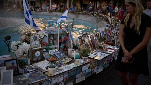 Menschen schauen auf Fotos von Israelis, die bei dem Überfall ums Leben gekommen sind.