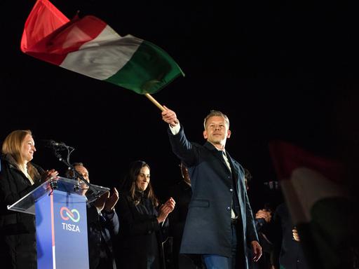 Peter Magyar schwenkt nach seinem Wahlsieg am 13. April 2026 eine ungarische Flagge.