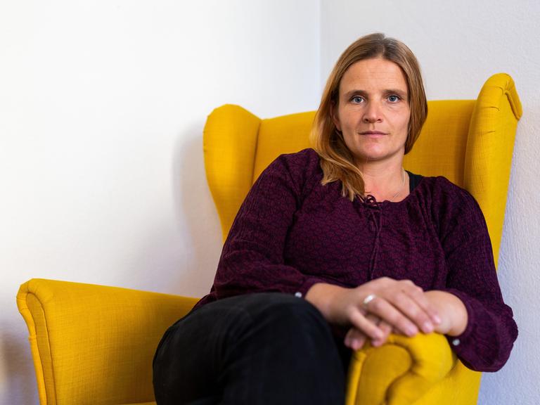 Sarah Pohl sitzt in einem gelben Sessel in ihrem Büro. 
