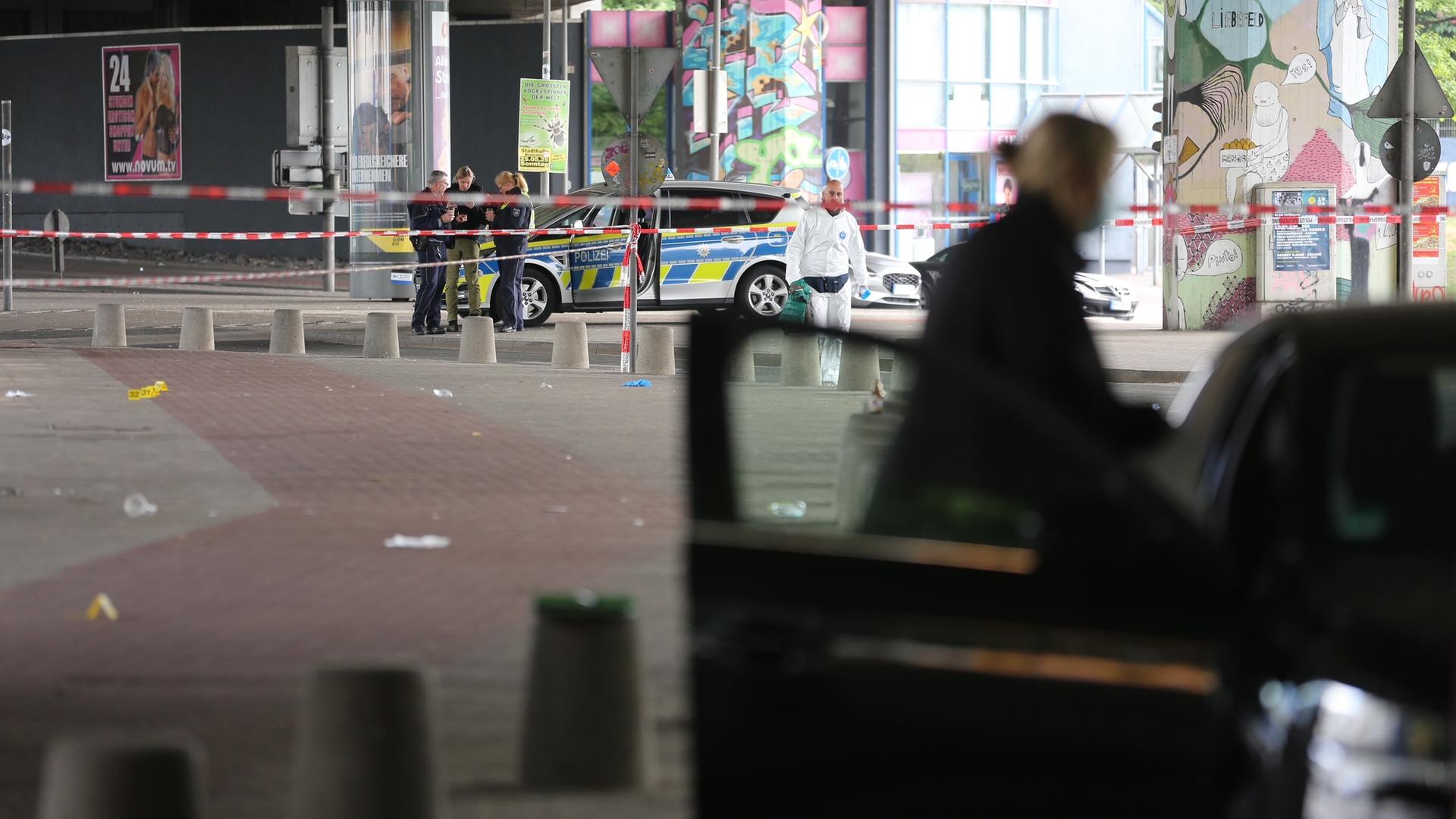 Beamte von Polizei und Spurensicherung untersuchen den Tatort. Ein Polizeiauto steht am Straßenrand. Beamte von Polizei und Spurensicherung untersuchen den Tatort. Ein Polizeiauto steht am Straßenrand.
