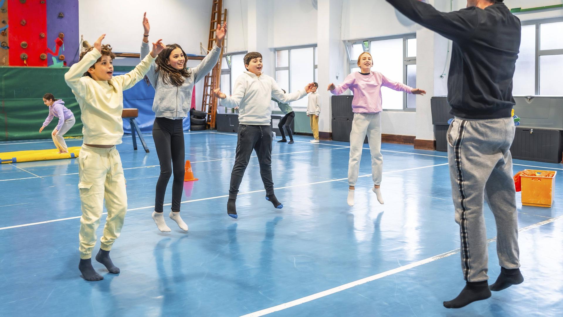 Symbolbild: Schüler machen zusammen mit ihrem Sportlehrer in der Schule Hampelmänner und Fitnessübungen. Symbolbild: Schüler machen zusammen mit ihrem Sportlehrer in der Schule Hampelmänner und Fitnessübungen.