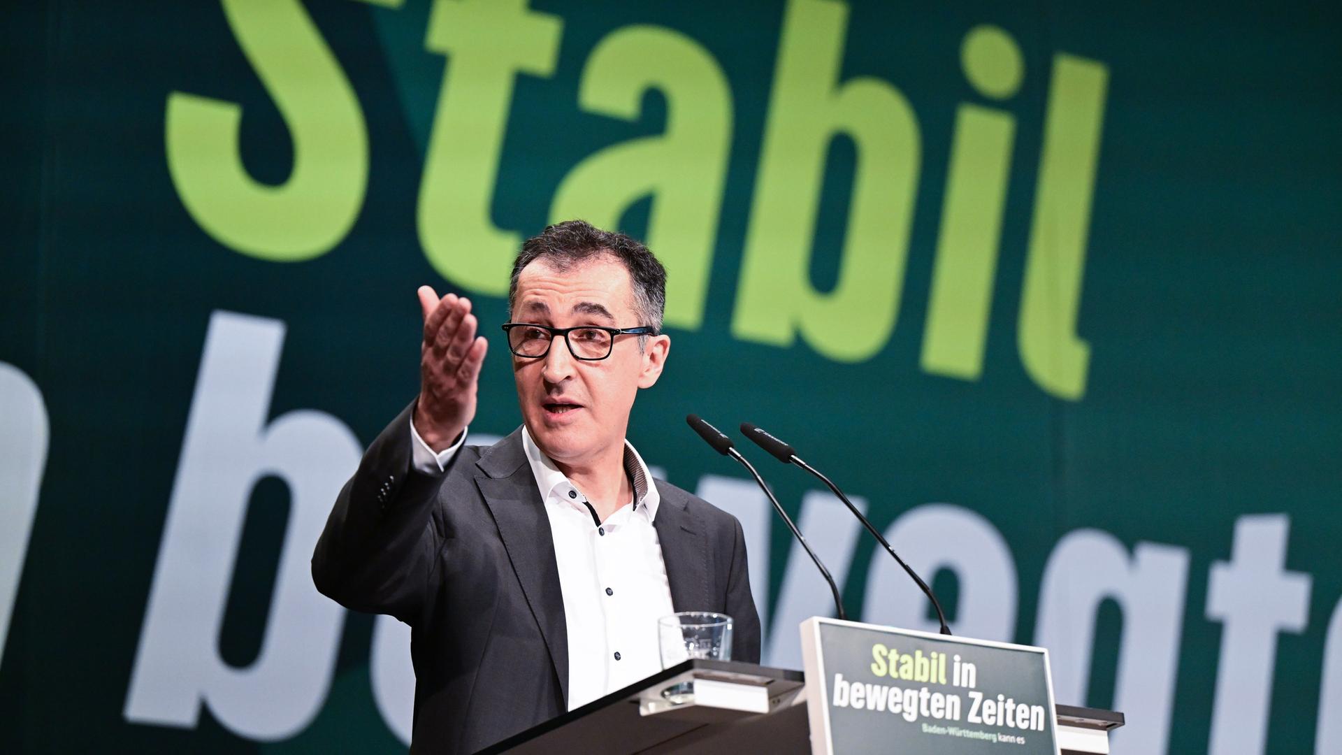 Ein Mann im Anzug und mit Brille steht an einem Rednerpult. Er spricht und gestikuliert mit einer Hand. Ein Mann im Anzug und mit Brille steht an einem Rednerpult. Er spricht und gestikuliert mit einer Hand.