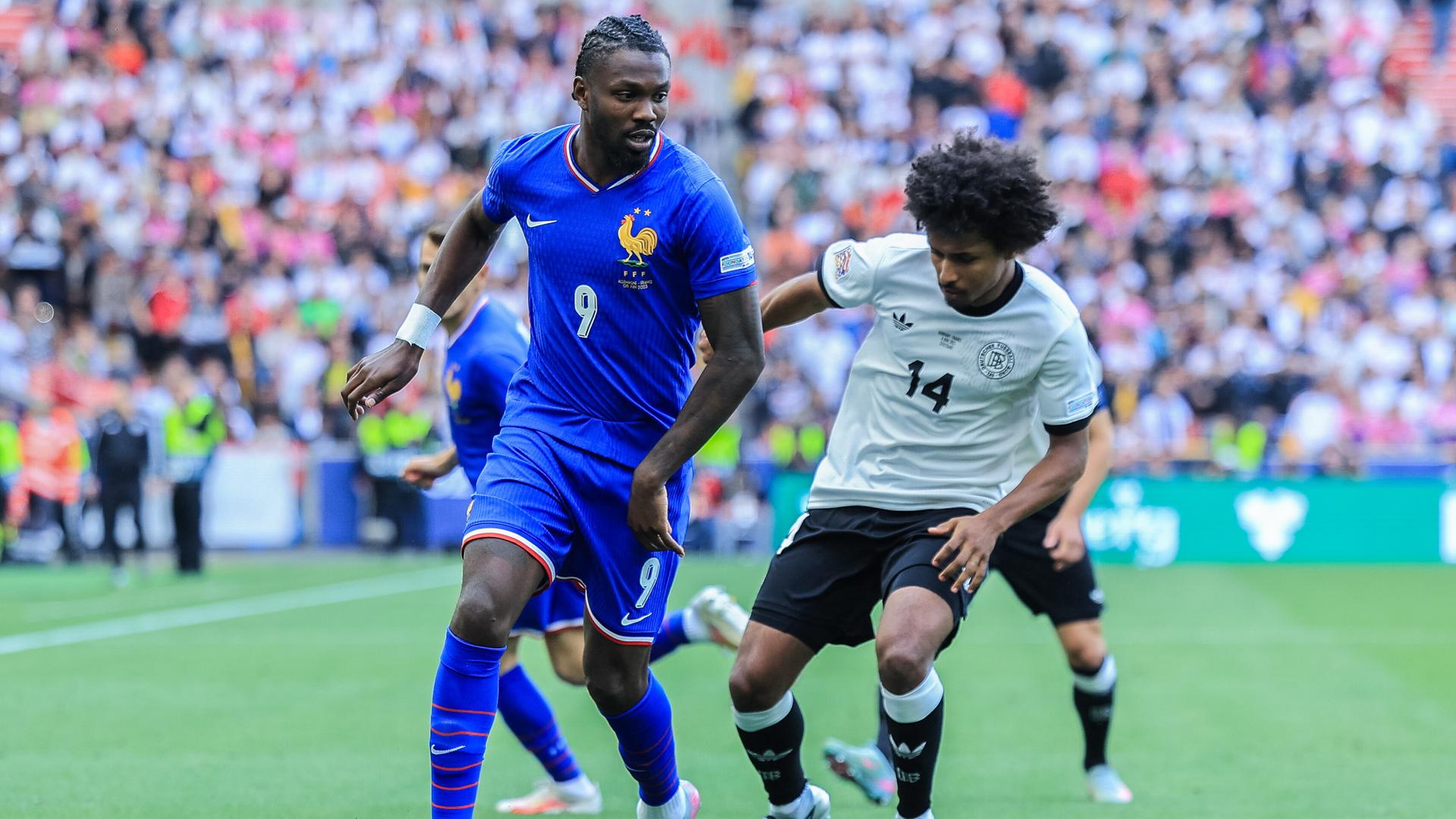 Das Bild zeigt eine Spielszene aus der Partie um Platz 3 zwischen Deutschland und Frankreich. Marcus Thuram ( Frankreich ), links, im Duell mit Karim Adeyemi.