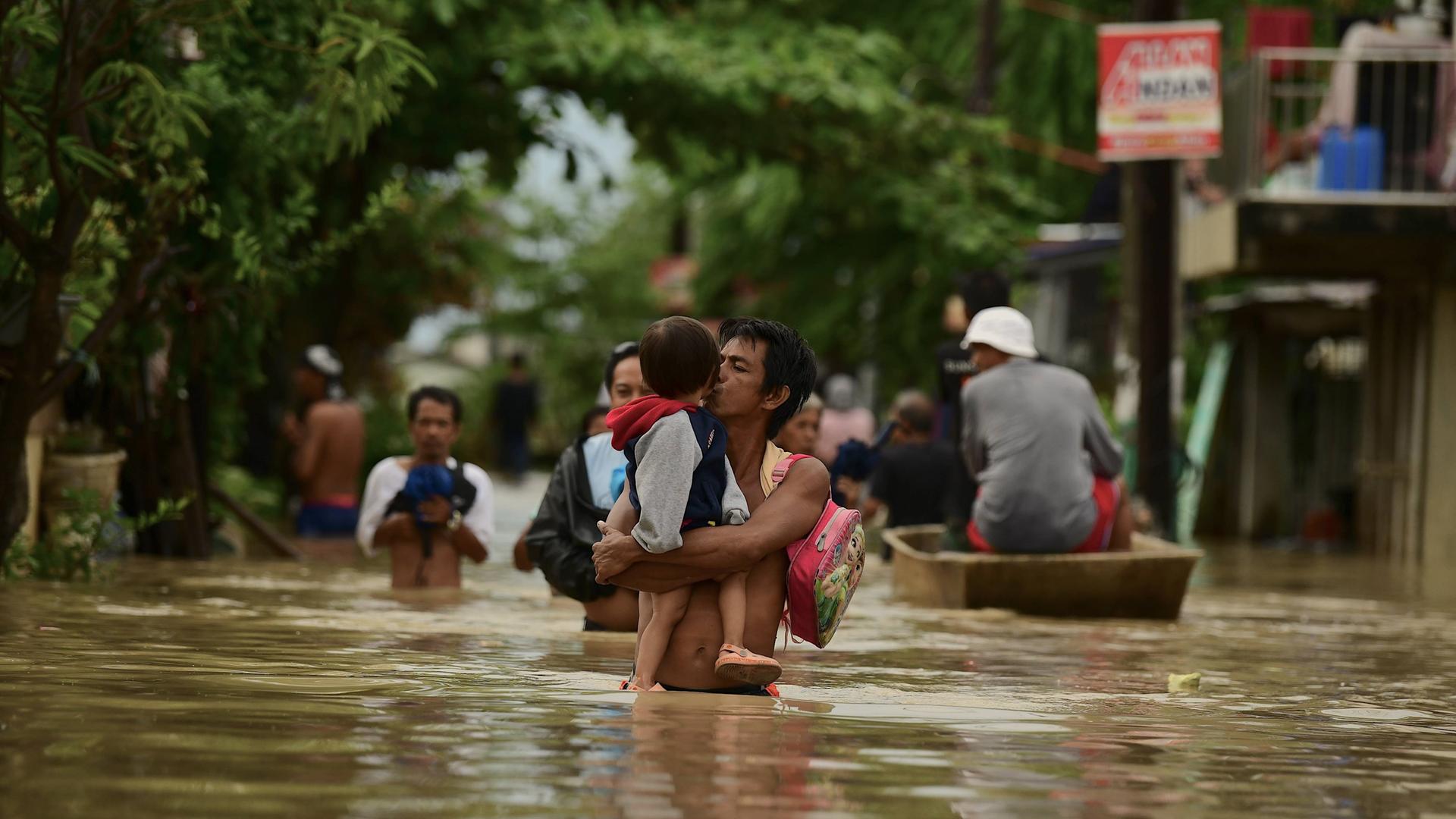 Mehrere Menschen in einer überschwemmten Gegend auf den Philippinen.