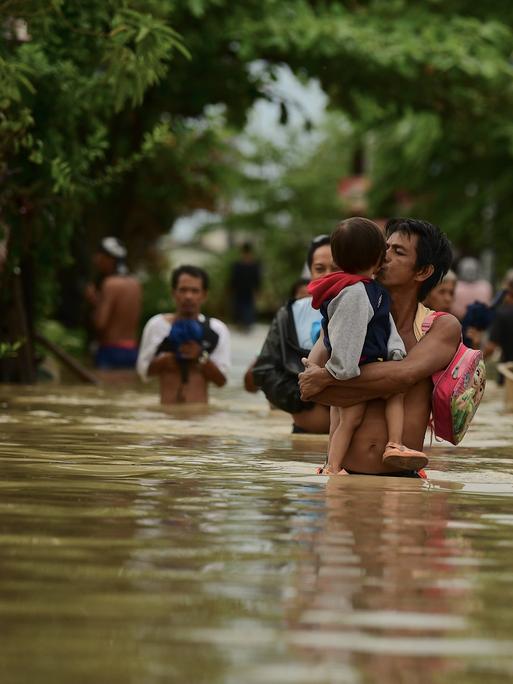 Mehrere Menschen in einer überschwemmten Gegend auf den Philippinen.